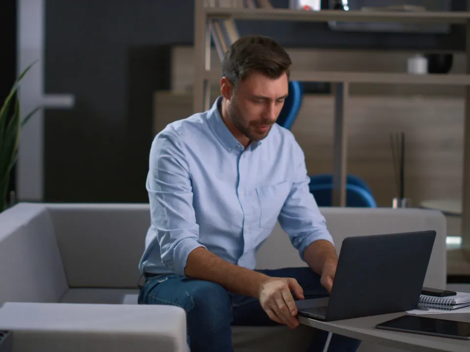 Eine Person aus dem Vertrieb im Video-Call am Laptop in einem modernen Büro